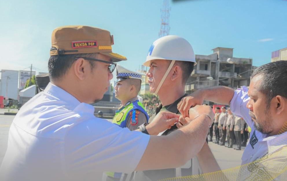 Plt Sekdako Padangsidimpuan saat menyematkan pita operasi kepada perwakilan pasukan operasi Keselamatan Toba 2024 di Alaman Bolak Padang Nadimpu, Rabu (13/3-24). Foto : BP/Ist
