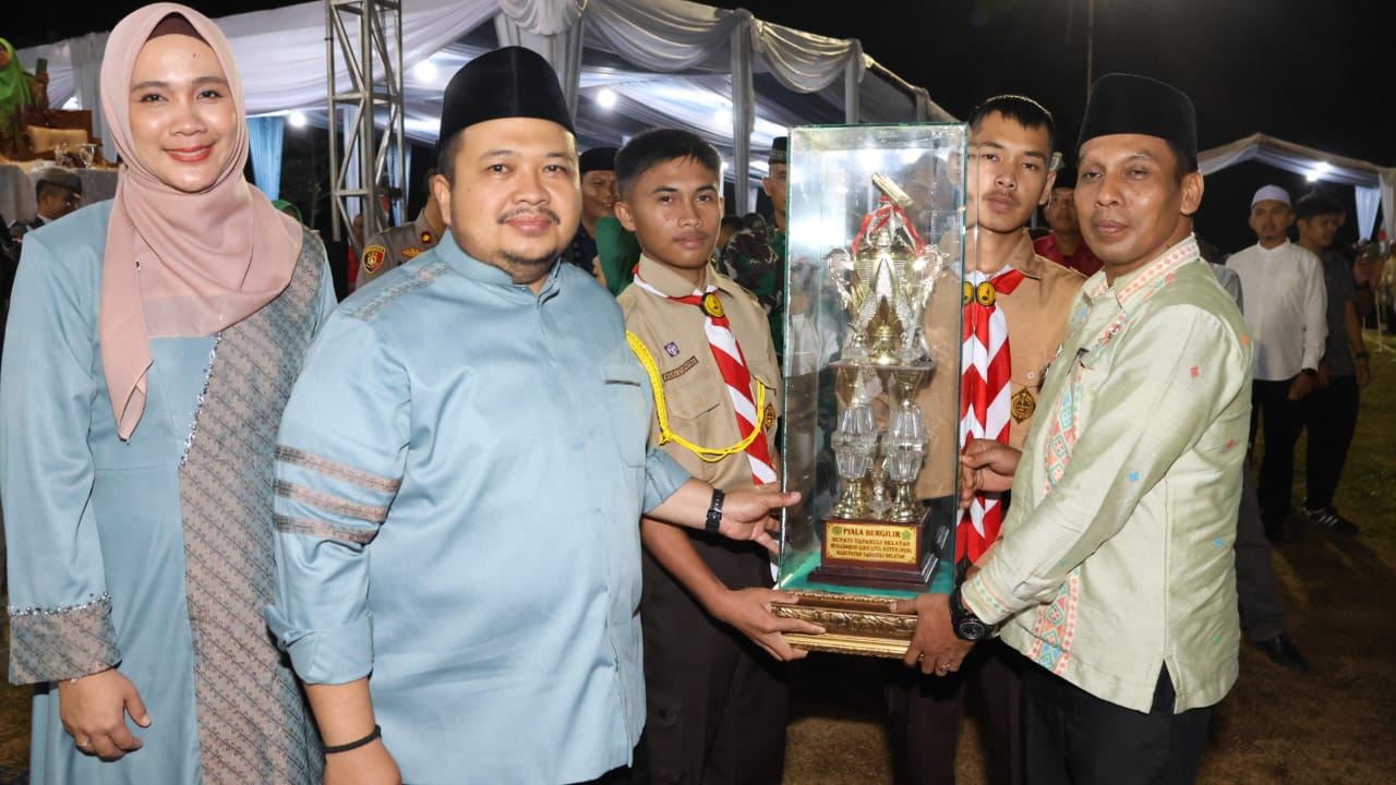 Bupati Tapsel Dolly Pasaribu saat menyerahkan Piala kepada Kecamatan Muara Batangtoru yang meraih Juara Umum MTQ ke-56 tahun 2024 tingkat Tapsel usai penutupan MTQ tersebut. Minggu (28/4-24) malam. Foto : BP/Ist