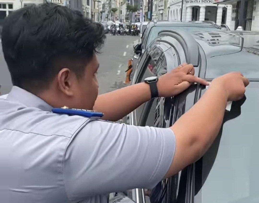 Petugas dishub Medan memasang stiker parkir Berlangganan ke mobil.