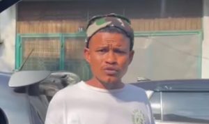 seorang pria memakai baju putih yang meminta uang parkir kepada seorang pengendara di Medan, meskipun kendaraan tersebut telah memiliki stiker parkir berlangganan.