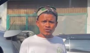 seorang pria memakai baju putih yang meminta uang parkir kepada seorang pengendara di Medan, meskipun kendaraan tersebut telah memiliki stiker parkir berlangganan.