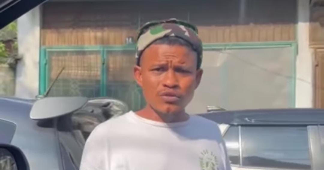 seorang pria memakai baju putih yang meminta uang parkir kepada seorang pengendara di Medan, meskipun kendaraan tersebut telah memiliki stiker parkir berlangganan.