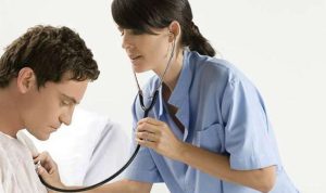 Seorang dokter sedang memeriksa pasien dengan stetoskop, mengingatkan pentingnya diagnosis profesional dibandingkan self-diagnosis.