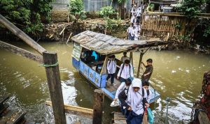 Foto Momen pelajar menggunakan perahu eretan di Kali Pesanggrahan
