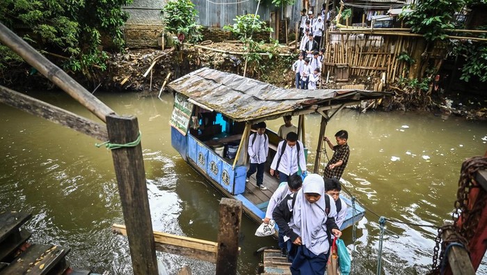 Foto Momen pelajar menggunakan perahu eretan di Kali Pesanggrahan