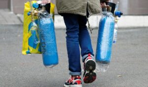 Seorang pria membawa tabung oksigen saat memasuki rumah sakit untuk pasien yang terinfeksi Covid-19 di Kiev, Ukraina