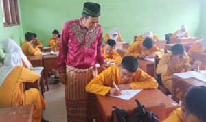 Seorang guru, Bustami Ramzi saat memberikan pelajaran kepada siswanya di SMP 10 Kecamatan Tapung, Kabupaten Kampar, Riau,
