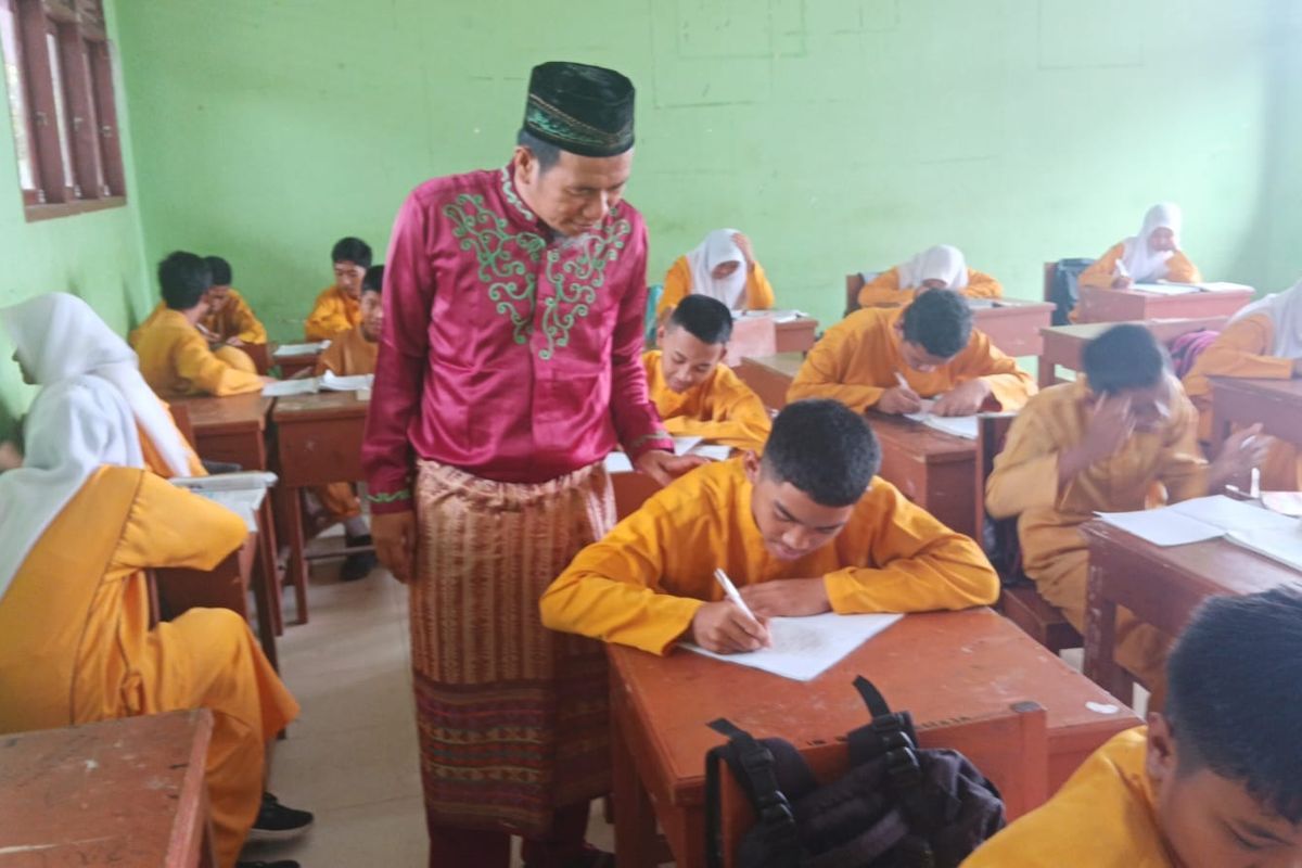 Seorang guru, Bustami Ramzi saat memberikan pelajaran kepada siswanya di SMP 10 Kecamatan Tapung, Kabupaten Kampar, Riau,