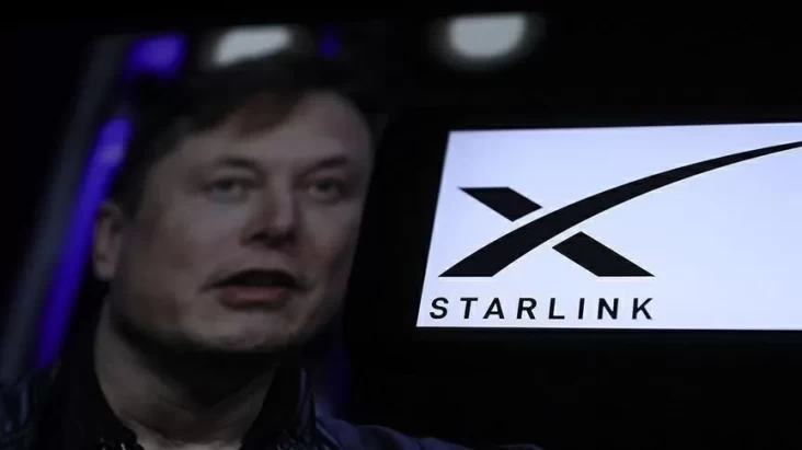 Elon Musk terlihat di layar dekat logo Starlink