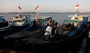 Warga menurunkan sepeda motor dari sebuah kapal kayu saat tiba dari Balikpapan