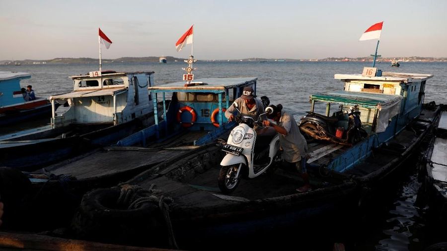 Warga menurunkan sepeda motor dari sebuah kapal kayu saat tiba dari Balikpapan