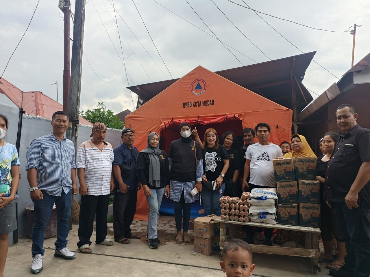 Anggota AMS XII Kota Medan menyerahkan bantuan sembako kepada korban kebakaran. Suasana penuh kepedulian dan kebersamaan.
