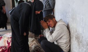 Seorang wanita mencoba menenangkan kerabatnya di samping jasad korban tewas akibat serangan Israel di Kota Gaza