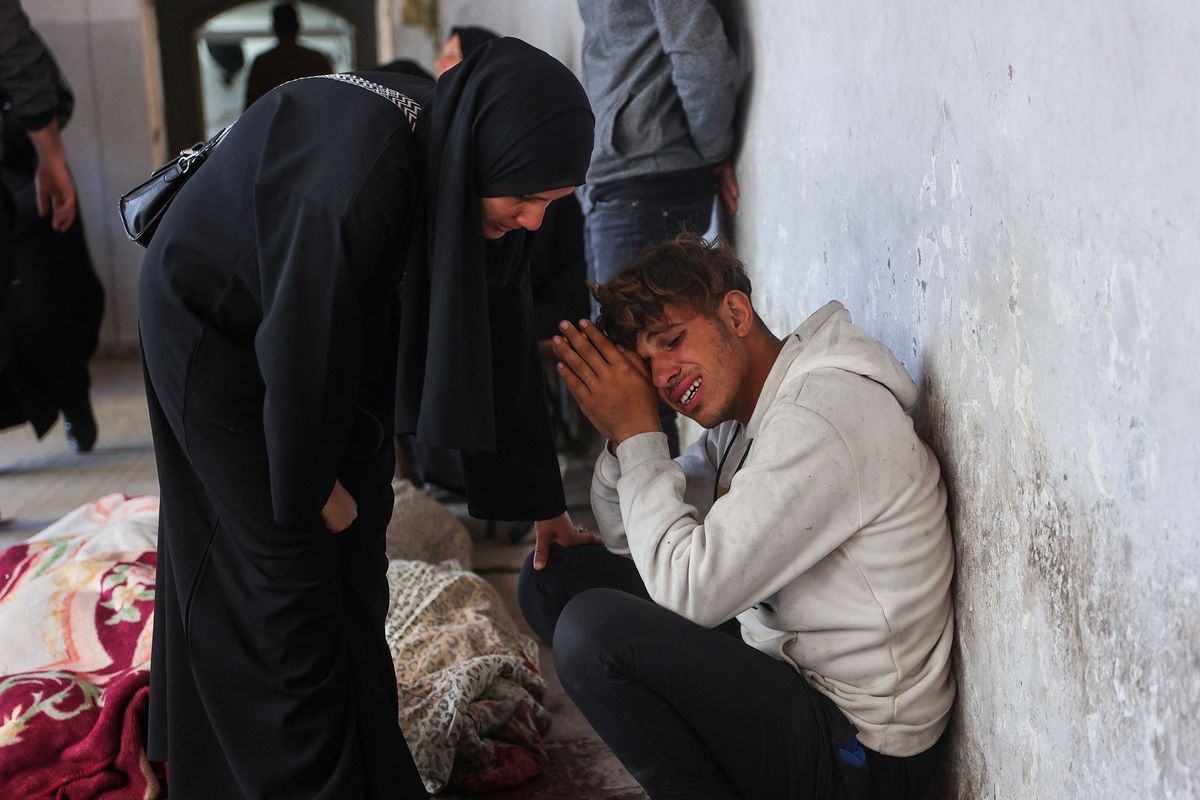 Seorang wanita mencoba menenangkan kerabatnya di samping jasad korban tewas akibat serangan Israel di Kota Gaza