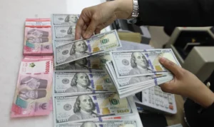 Karyawan memperlihatkan uang Rupiah dan dolar AS di salah satu tempat penukaran uang asing di Jakarta
