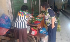 Ibu Hutabarat pedagang sayuran Pasar Petisah (kiri) saat melayani pembeli di Pasar Petisah Medan, Rabu (26/3/2025). BP/erwan