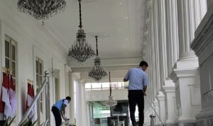 Petugas tampak sedang bersih-bersih, mengepel lantai area pilar Kompleks Istana Kepresidenan