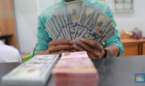 Petugas menghitung uang di tempat penukaran uang Dolar Asia