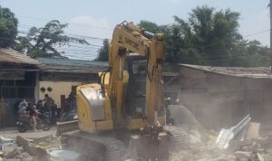 Sebuah ekskavator dikerahkan untuk membongkar bangunan liar di bantaran Kali Baru, Desa Sumberjaya, Tambun Selatan (detik.com)